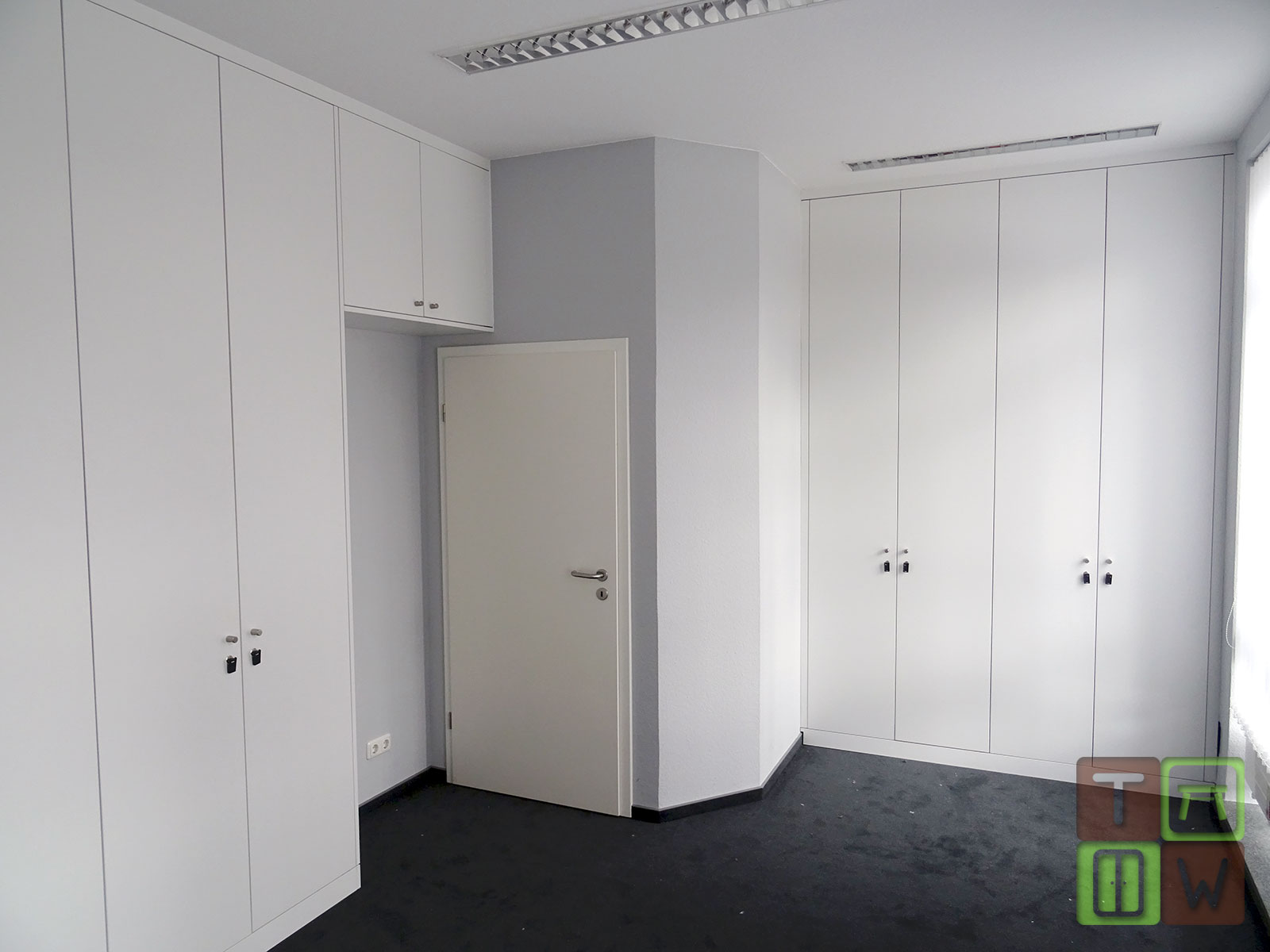 Gesamtes Büro, bei dem zwei Wände vollständig mit Einbauschränken ausgestattet wurden.