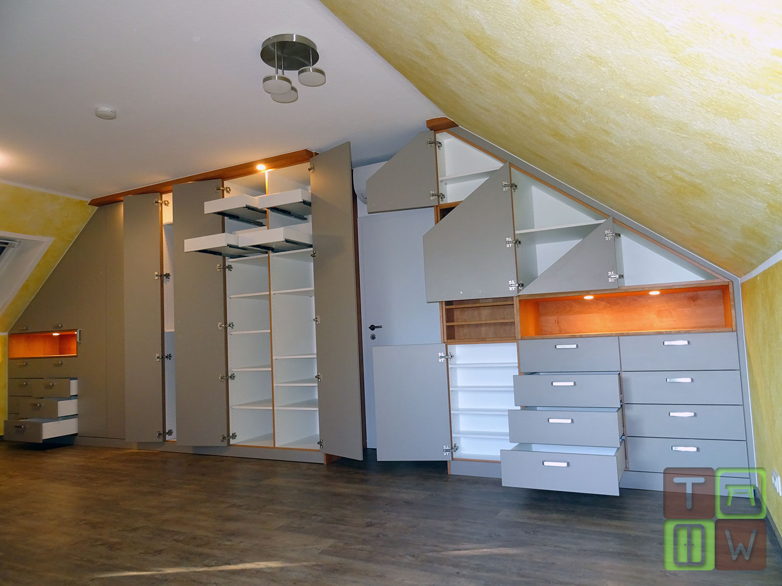Komplette Wand mit Einbauschrank in doppelter Dachschräge mit geöffneten Türen und Schubläden